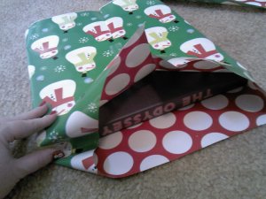 Next, use your thumb to tuck in the center pieces of the outside edges of the wrapping paper.  There is Monsieur le Snowhomme sneaking into the photo on my thumbnail.